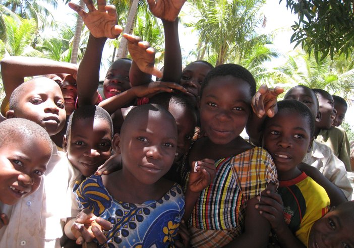 A group of children, bunched together looking at the camera and smiling