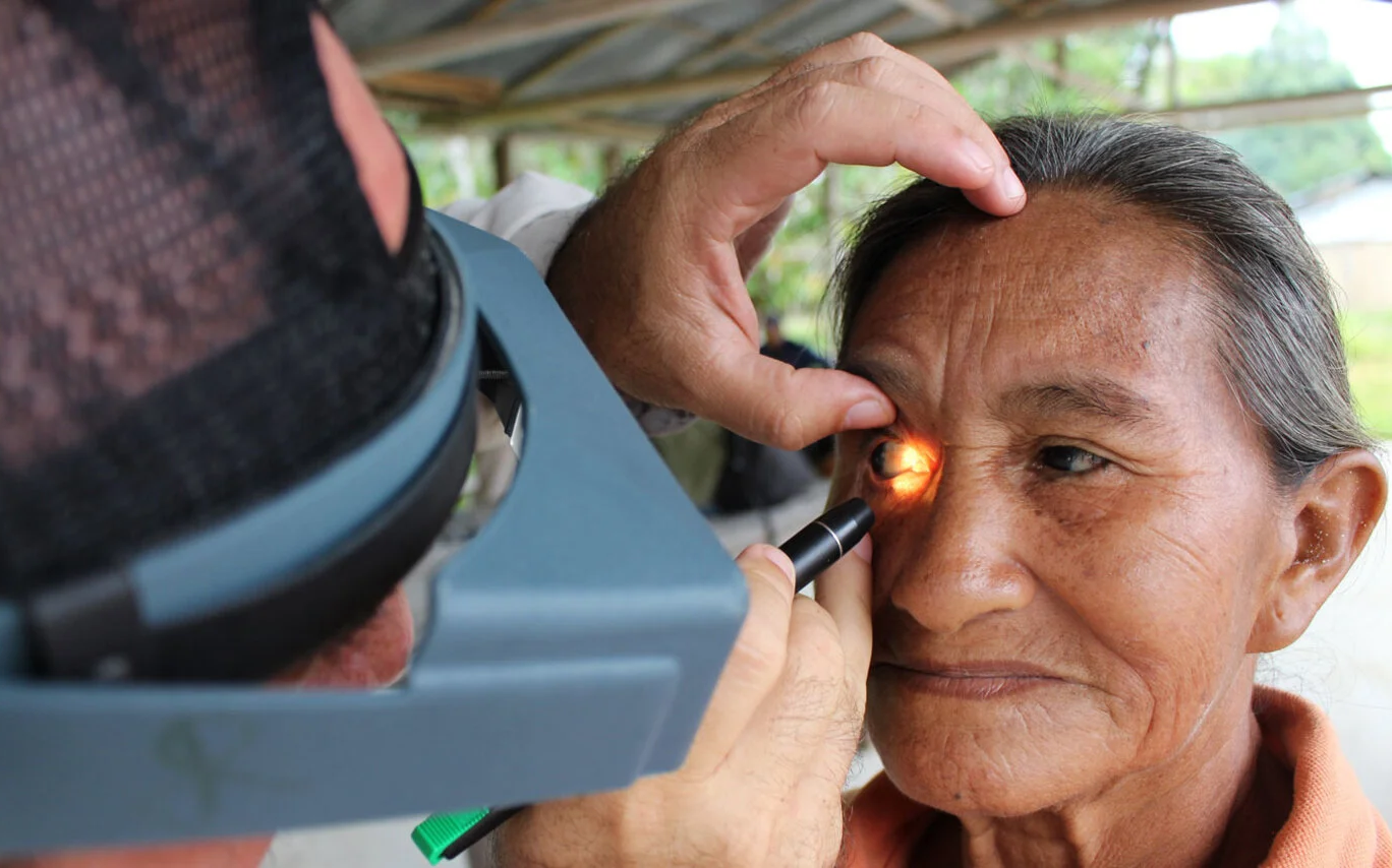 A health worker shines a torch into a lady's eye